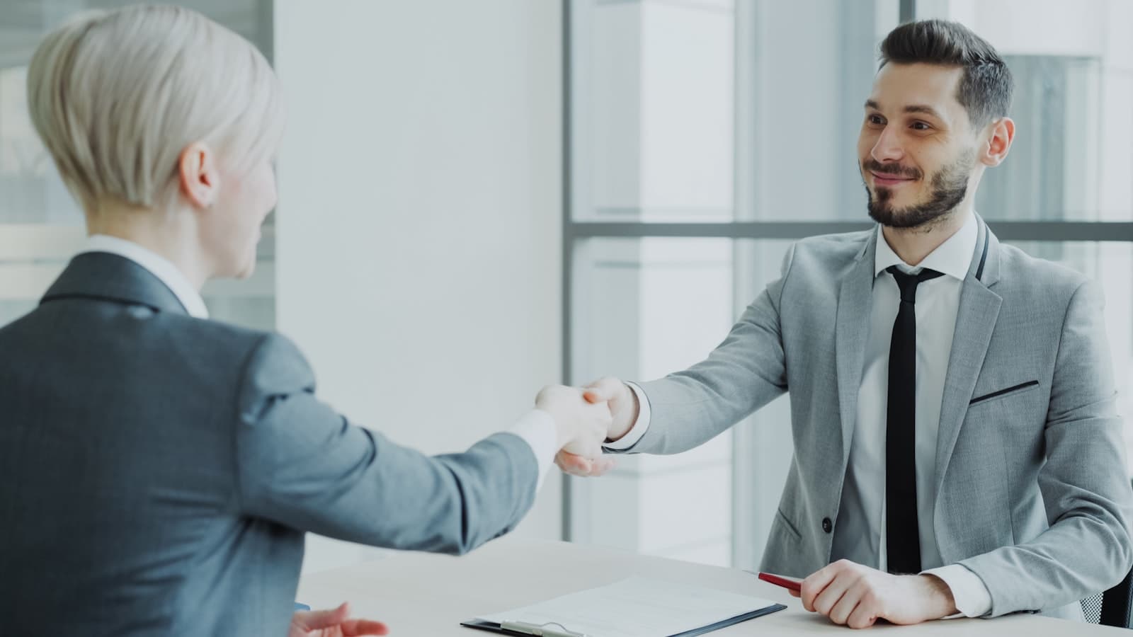 Two professionals shaking hands across a table
